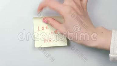 特写女人`她的手贴着黄色的贴纸纸，上面写着让它成为。